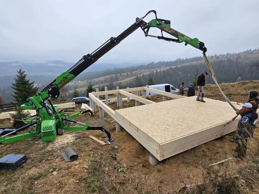 Mini-grue araignée avec stabilisateurs déployés lors de travaux de construction
